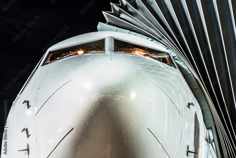 Airplane parked at the airport at night, view nose cockpit close up ...