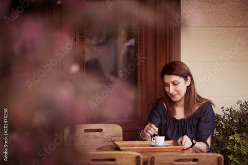 Young woman drinking coffee in a cafe outdoors. Brown toning