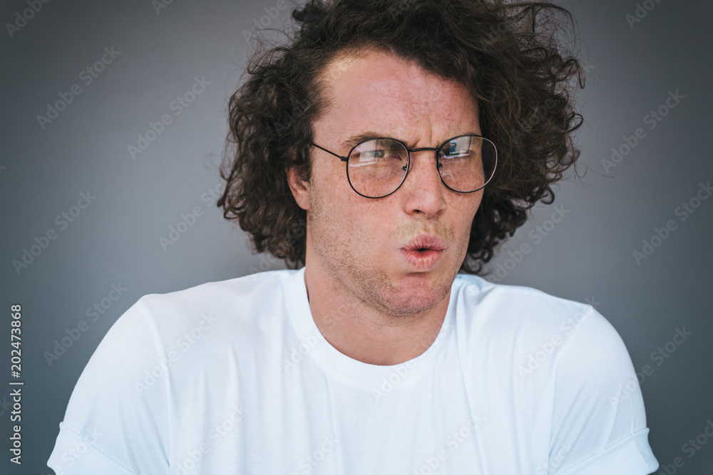 Caucasian handsome male with curly hair has frustrated emotion after seeing something desgusting. Student man forget some exams. Copy space for advertisement Caucasian handsome male with curly hair has frustrated emotion after seeing something desgusting. Student man forget some exams. Copy space for advertisement