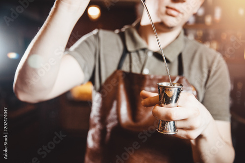 Close-up of barman pours into alcohol into measuring glass