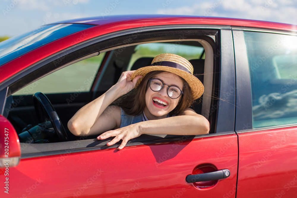 Young woman in car. Girl driving a car.  Smiling young woman sitting in red car
