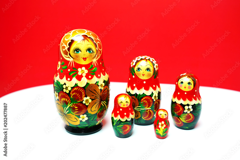 Matryoshka traditional Russian wooden dolls;Russian souvenir Matrioshka ;Nesting dolls  on red and white  background bring in affluent , richly and wealthy.