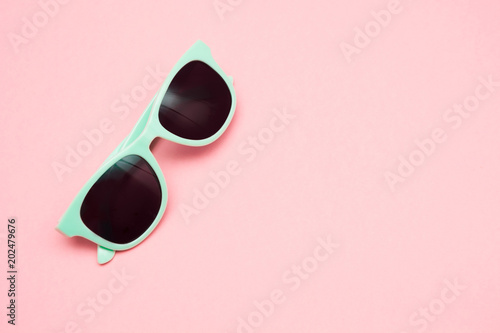 Green pastel sunglasses isolated on punchy pink, top view. Copy space. Summer concept.