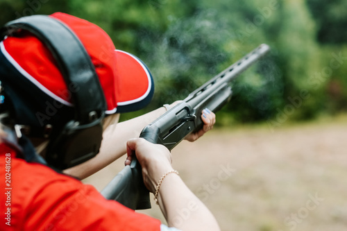 woman shooter headphones shoots hunting rifle smoke shot