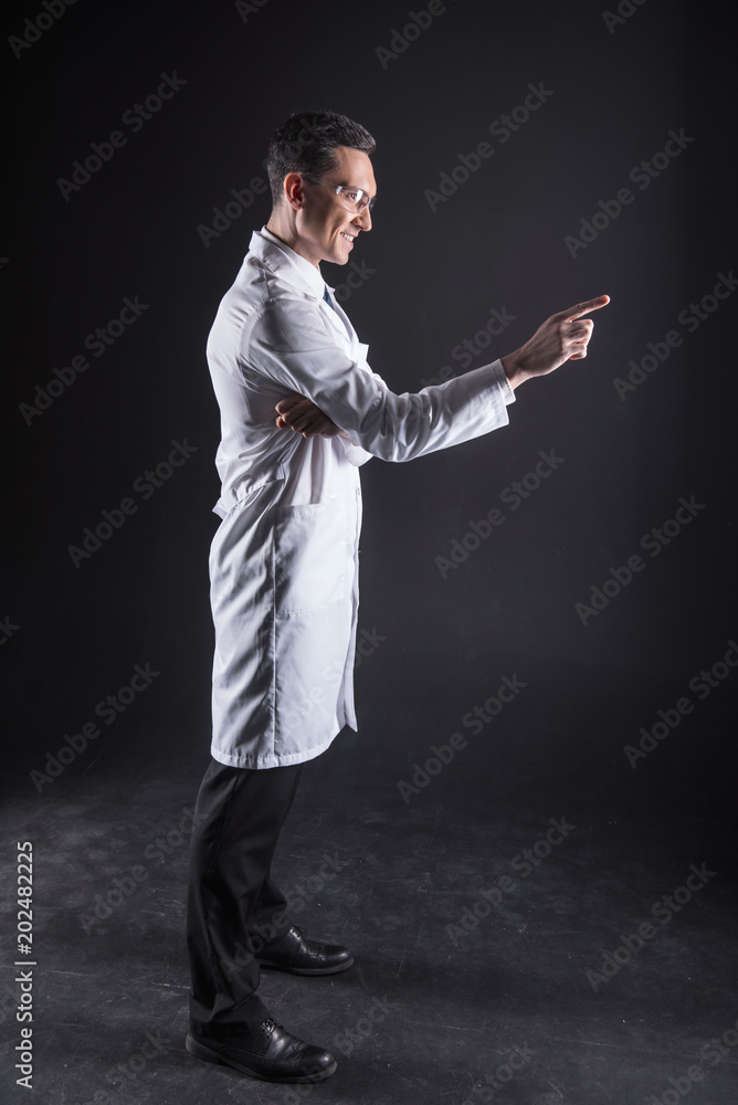 Protective equipment. Delighted positive male scientist standing and working on the computer screen while being in modern lab Protective equipment. Delighted positive male scientist standing and working on the computer screen while being in modern lab