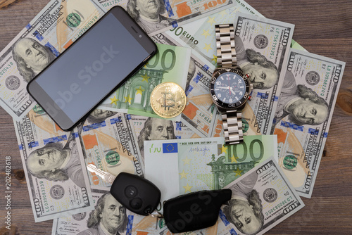 Car key, chronograph and gold bitcoin on Euro and Dollars banknotes background photo