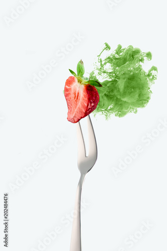 half of strawberry on fork and green ink isolated on white