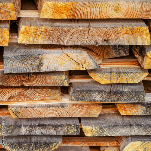Stack of stacked Lumber. Dried wood boards with a crack. Different types of wood. Square. Toned.