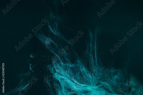 abstract artistic background with turquoise paint flowing on black