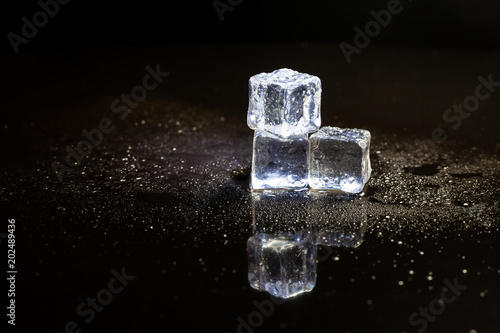 ice cubes reflection on black table background.