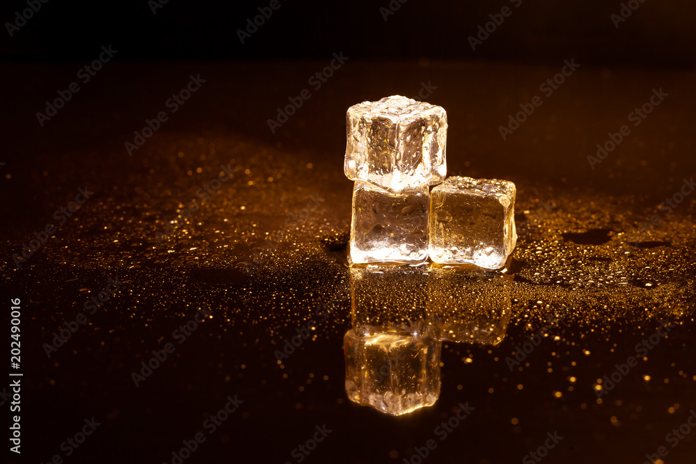 Golden ice cubes reflection on black table. Golden ice cubes reflection on black table.