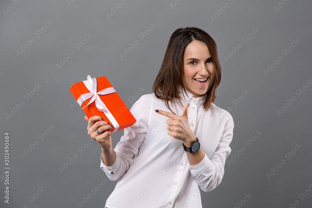 Great present. Delighted nice woman smiling while pointing at the gift box Great present. Delighted nice woman smiling while pointing at the gift box