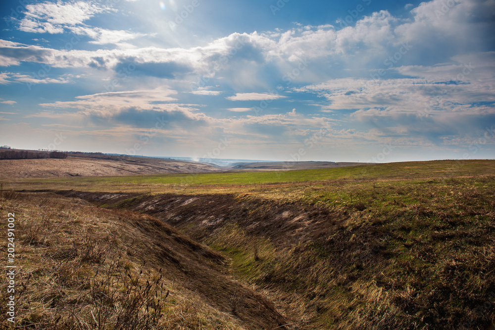 Countryside landscape, Hills with yellow and green grass and blue sky with clouds, spring landscape Countryside landscape, Hills with yellow and green grass and blue sky with clouds, spring landscape