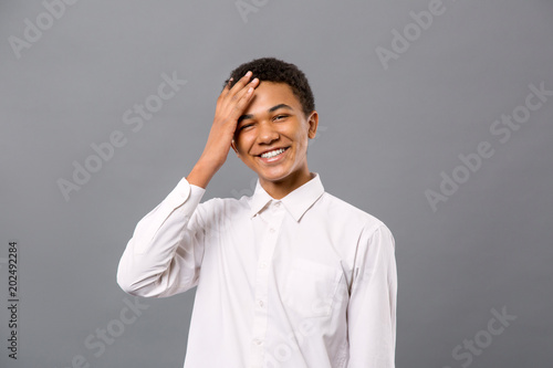 Young teenager. Delighted young man touching his forehead while smiling photo