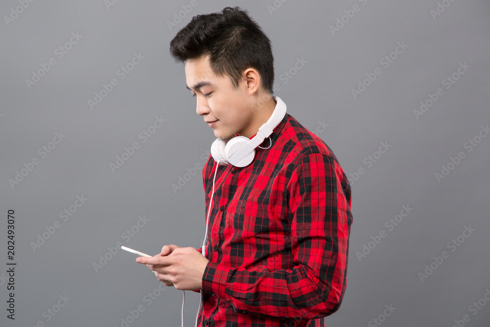 Modern technology. Smart young man wearing headphones while using his smartphone Modern technology. Smart young man wearing headphones while using his smartphone