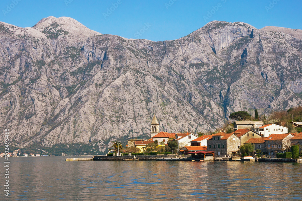 Small Mediterranean village with stone houses with red roofs against gray mountains. Montenegro, Bay of Kotor ( Adriatic Sea ), Stoliv village