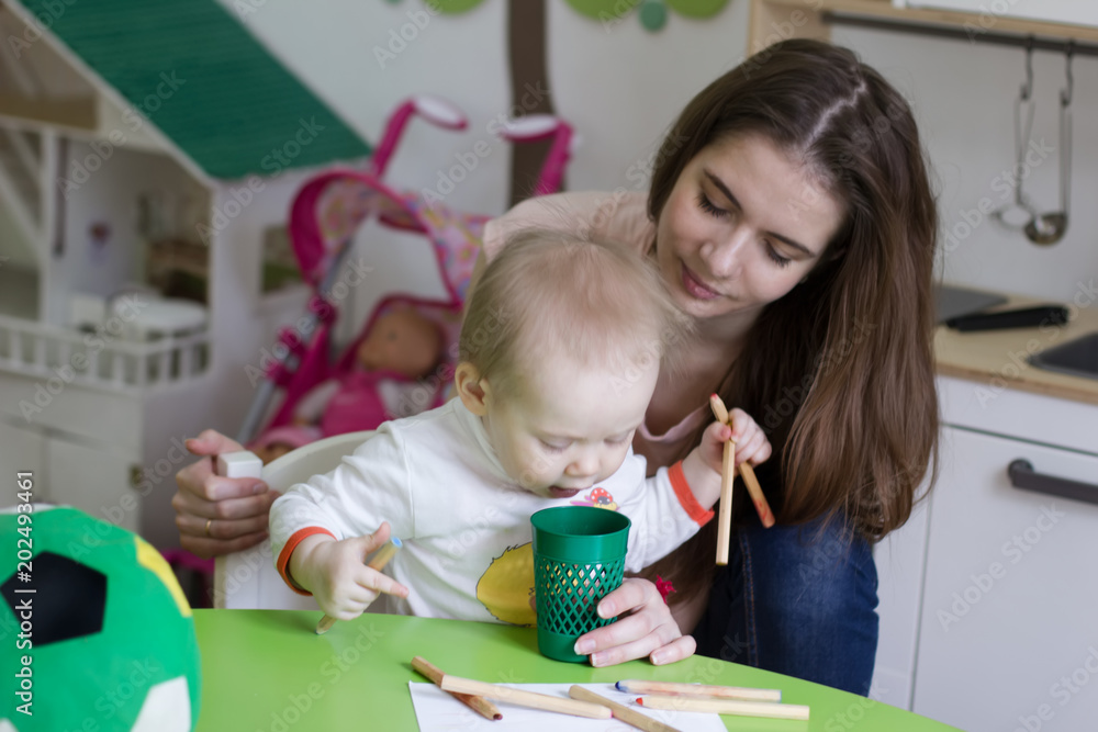 Fototapeta premium Mother playing with her 1,3 years old daughter, drawing together