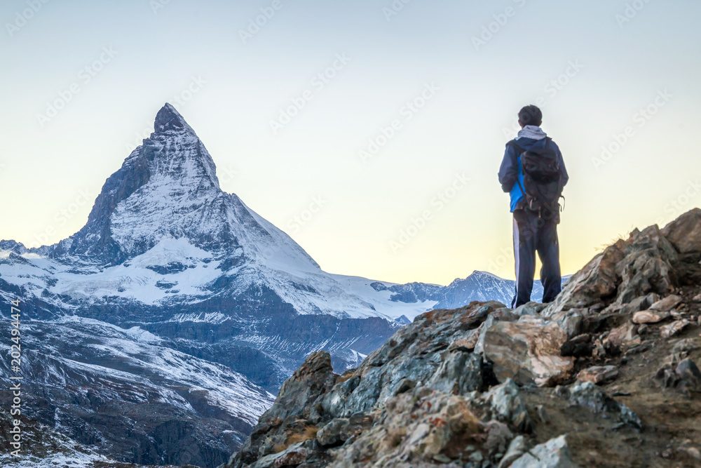 Junger Mann beim Bergsteigen in den Schweizer Alpen mit Matterhorn im Hintergrund