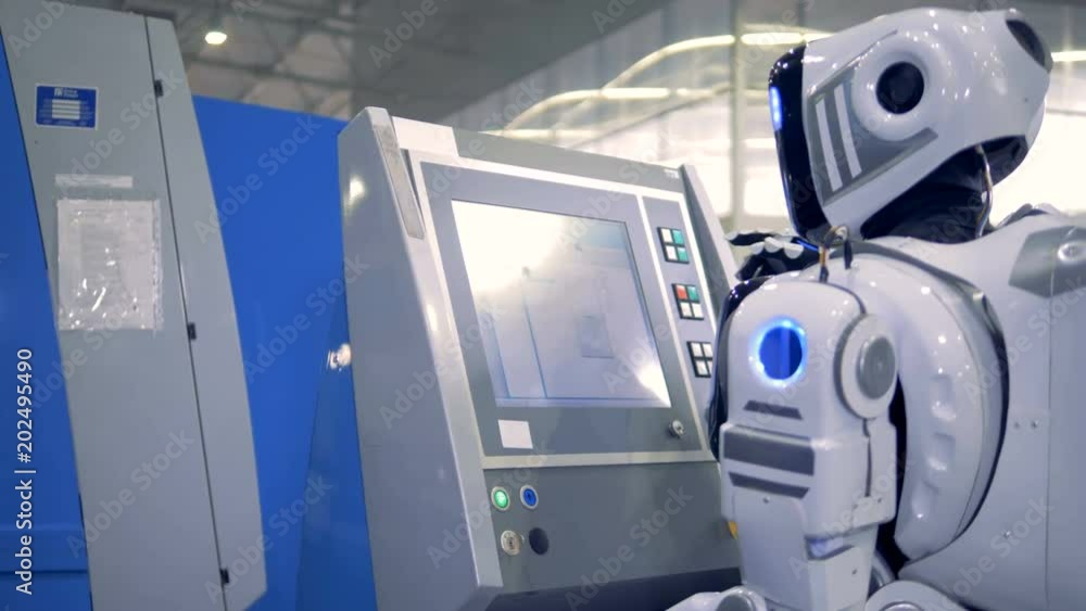 White robot works at a factory equipment using touchscreen monitor. White robot works at a factory equipment using touchscreen monitor.