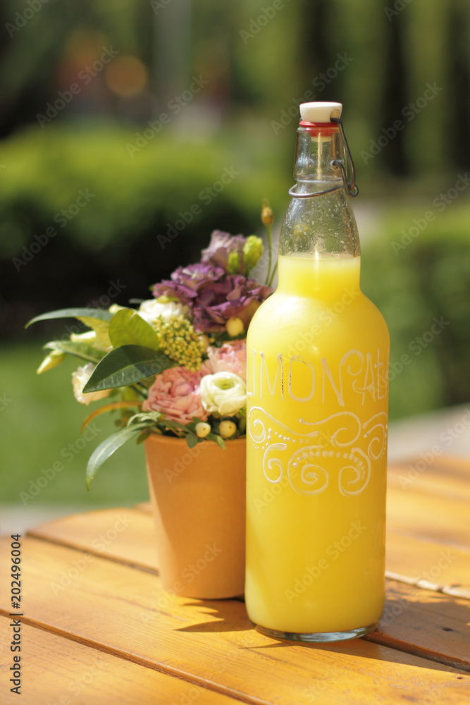 bottle of limonade on wooden table with small bouquet bottle of limonade on wooden table with small bouquet