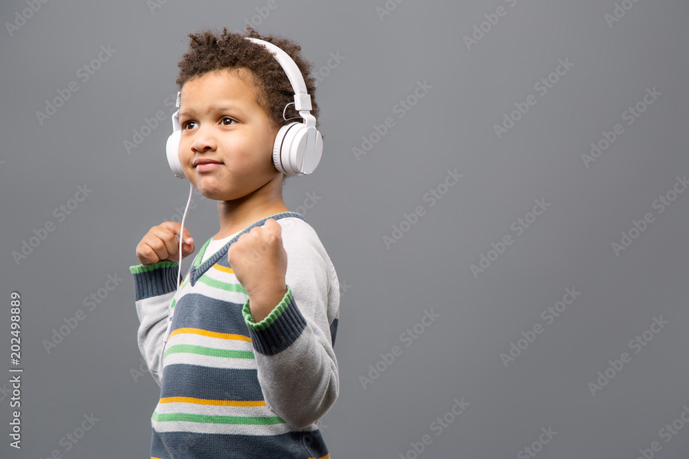 Leisure time. Joyful positive boy wearing headphones while listening to music Leisure time. Joyful positive boy wearing headphones while listening to music