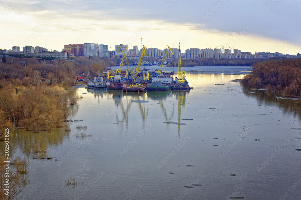 Ice drift on the Irtysh river in Siberia. Technical vessels parked in the backwater