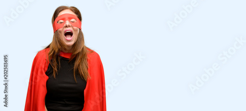 Middle age super hero woman wearing red mask and cape stressful, terrified in panic, shouting exasperated and frustrated. Unpleasant gesture. Annoying work drives me crazy isolated blue background