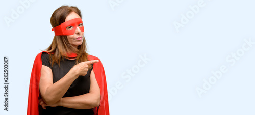 Foto Middle age super hero woman wearing red mask and cape pointing away side with fi