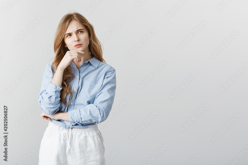 Do I really have to go on meeting. Portrait of focused serious caucasian girl with blond hair, touching chin and frowning, looking aside while thinking or recalling important information Do I really have to go on meeting. Portrait of focused serious caucasian girl with blond hair, touching chin and frowning, looking aside while thinking or recalling important information