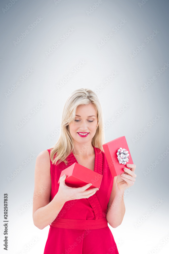Stylish blonde in red dress opening gift box on vignette background Stylish blonde in red dress opening gift box on vignette background