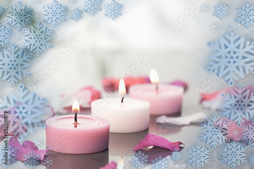 Composite image of lighted candles and petals against snowflake frame