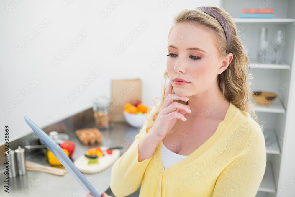 Thoughtful cute blonde using tablet Thoughtful cute blonde using tablet