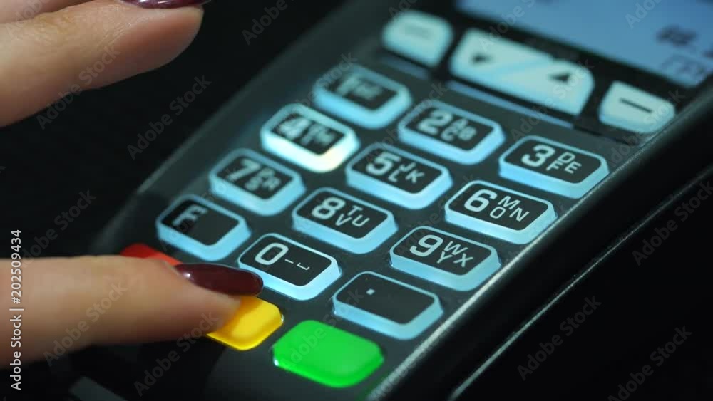 Shop assistant inserting a credit card into a pos and inserting pin-code of the card Shop assistant inserting a credit card into a pos and inserting pin-code of the card