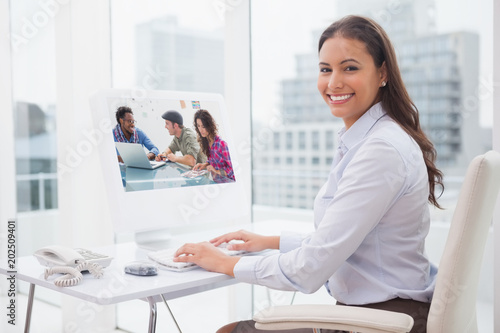 Creative team working together against smiling businesswoman working at her desk