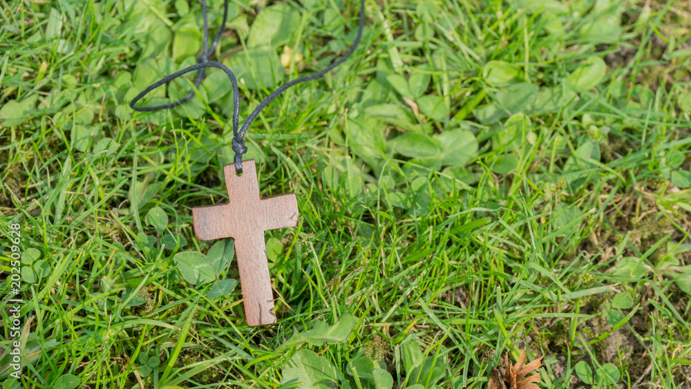 Holzkreuz Anhänger liegt auf dem Rasen Holzkreuz Anhänger liegt auf dem Rasen