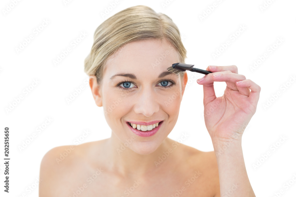 Cheerful young blonde woman brushing her eyebrow Cheerful young blonde woman brushing her eyebrow