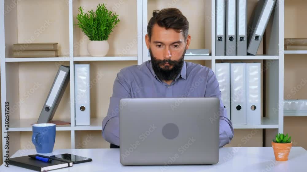 handsome worker reading good news in modern contemporary office. young man with beard and mustache celebrating win showing hand gesture yes.hipster excited about achieve success handsome worker reading good news in modern contemporary office. young man with beard and mustache celebrating win showing hand gesture yes.hipster excited about achieve success