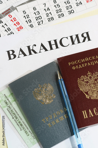 Calendar and Russian documents for employment: work book, passport and insurance certificate on the table. The inscription in Russian Vacancy