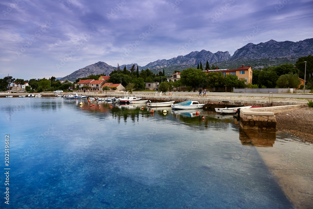 Yacht harbor with several motorboats on the background of beautiful mountains after sunset. Starigrad. Starigrad-Paklenica. Croatia.