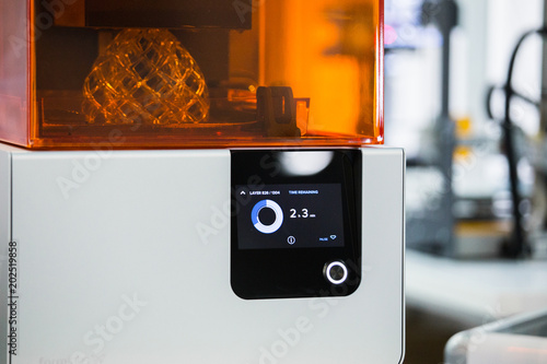 A stereolithography 3d printer in the laboratory prints a structure from a photopolymer.  On the display the process indicator and the number of layers. Creating scaled model by UV polymerization. photo