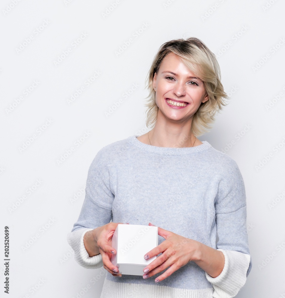 Happy girl with small white gift box. Small gift in the hands of a woman indoor. Happy girl with small white gift box. Small gift in the hands of a woman indoor.