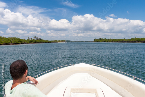 Man in boat looking at island in the sea of Bahia, Brazil. © Imago Photo