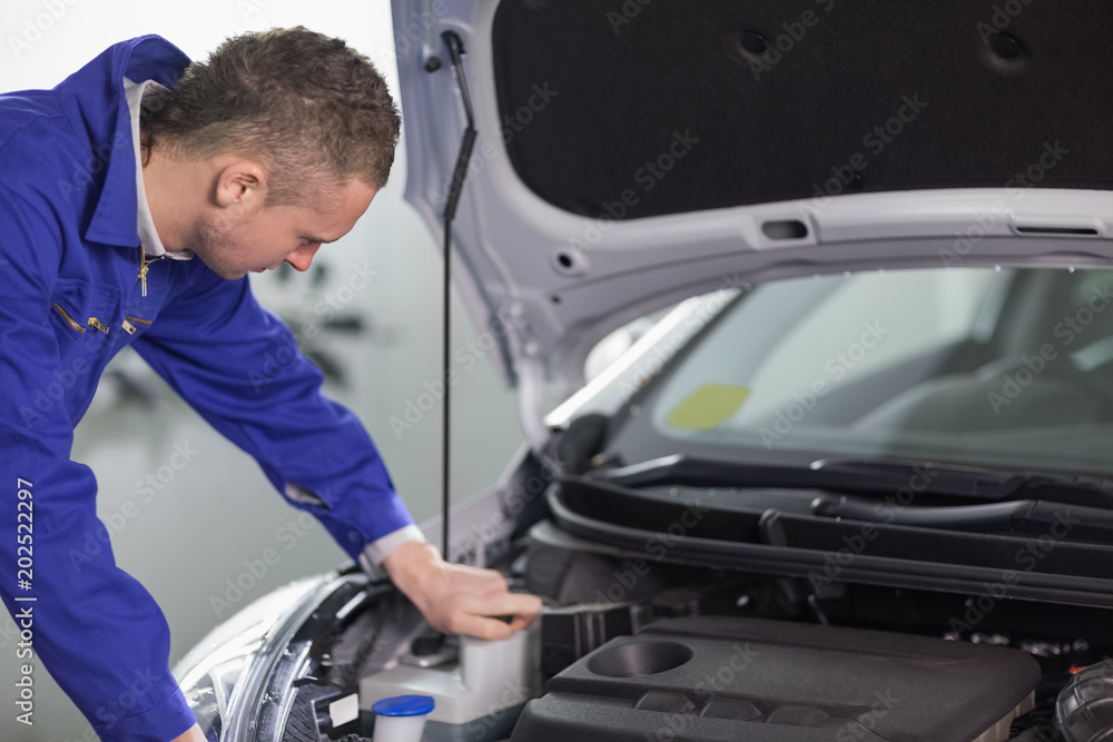 Mechanic looking at an engine while leaning on it Mechanic looking at an engine while leaning on it