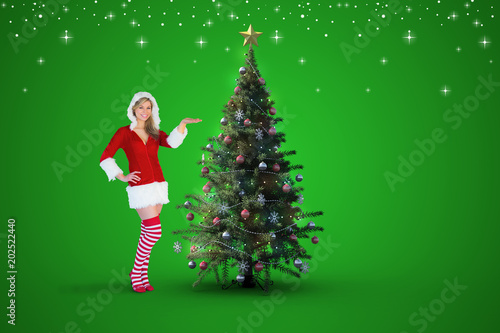 Pretty girl presenting in santa outfit against christmas tree