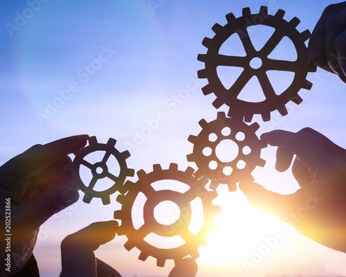 four hands of businessmen holding puzzle pieces of gears check mark icon. Business concept idea, cooperation, teamwork, creative strategy, choice.