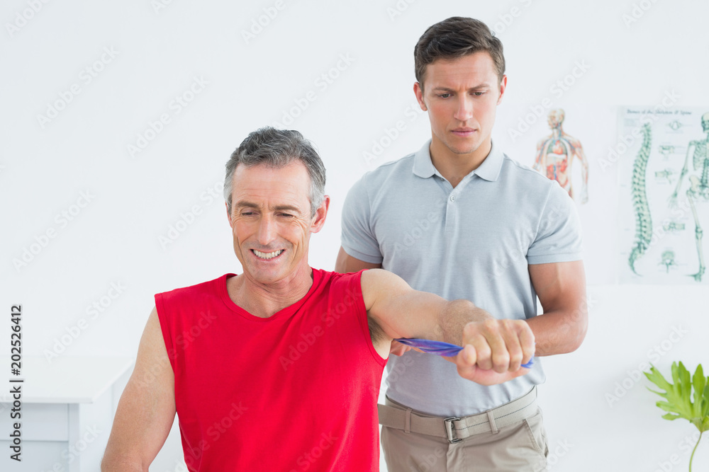Physiotherapist examining a smiling mature mans arm Physiotherapist examining a smiling mature mans arm