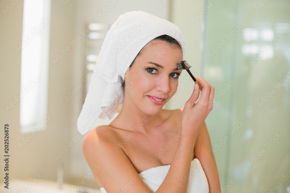 Content natural brown haired woman brushing her eyebrows Content natural brown haired woman brushing her eyebrows