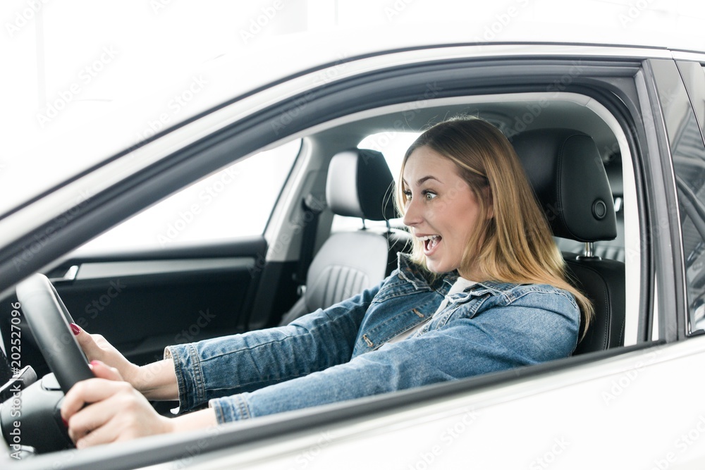 Screaming girl rides behind the wheel of a car