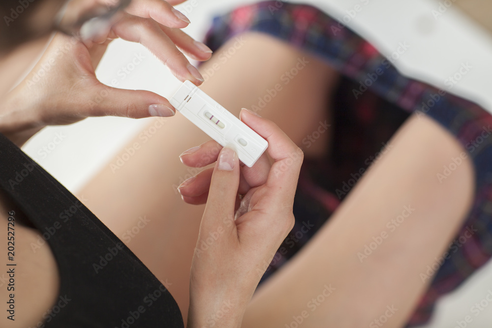 Obraz premium Woman holding in hands pregnancy test. She is expecting a baby.
