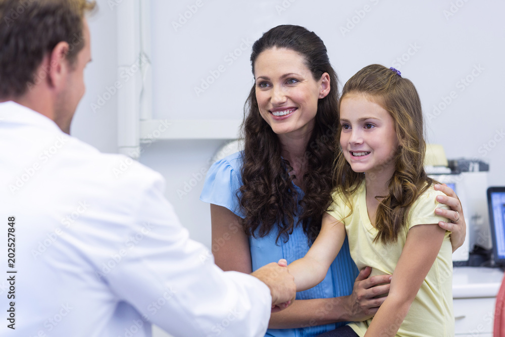 Dentist shaking hand with daughter after dental examination Dentist shaking hand with daughter after dental examination